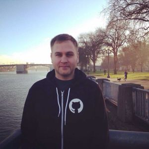 A man in a github sweatshirt is standing by a river